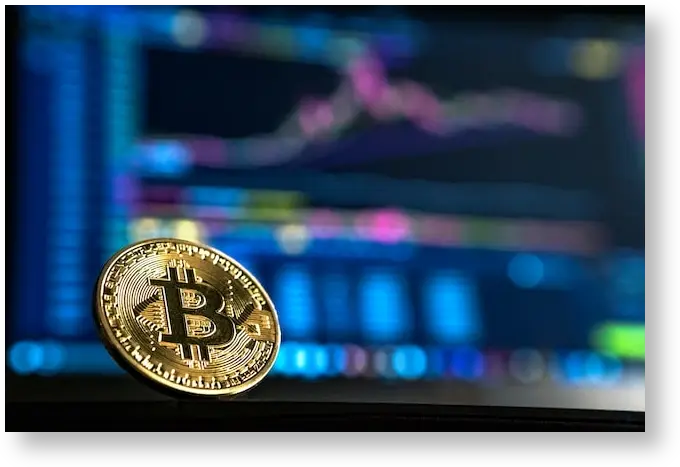 A bitcoin logo on a golden gold in front of trading charts