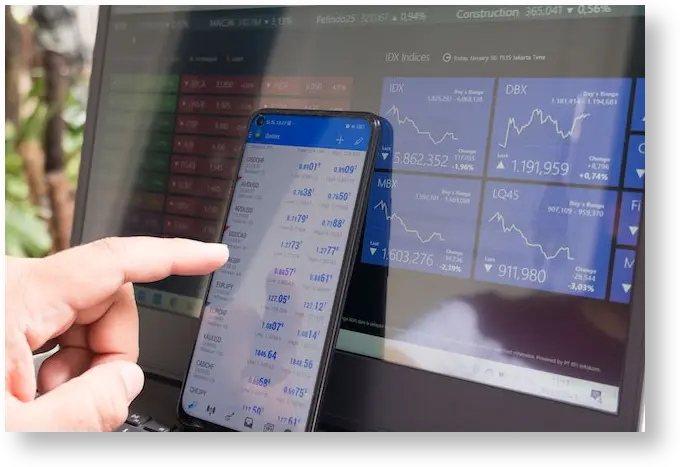 Person using a Metatrader application with a laptop full of trading charts